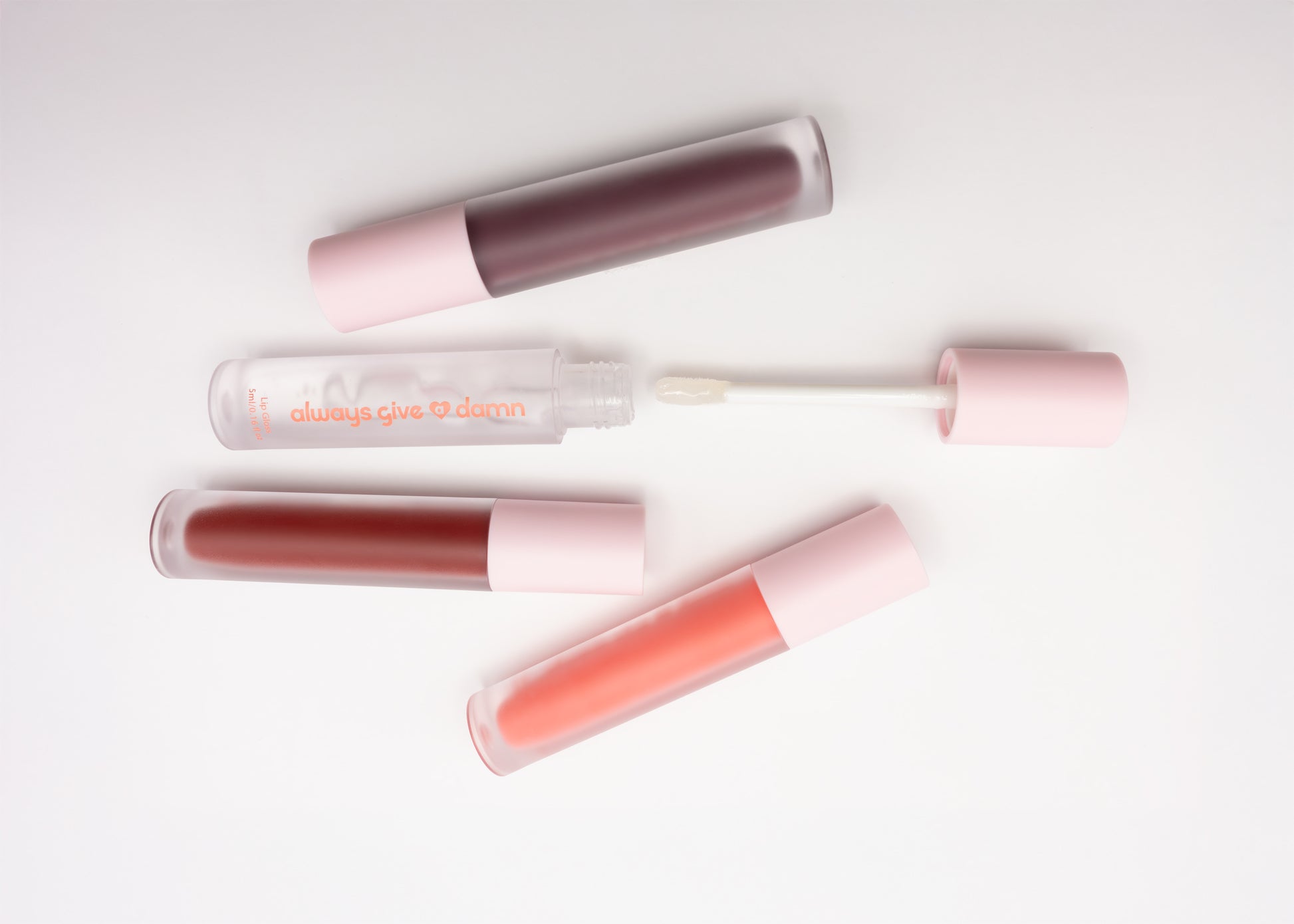 All four lip gloss shades including purple, clear, red, and pink